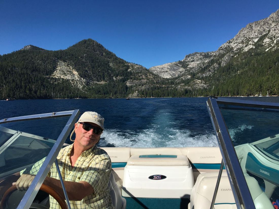 Terry at the wheel of a boat on a mountain lake