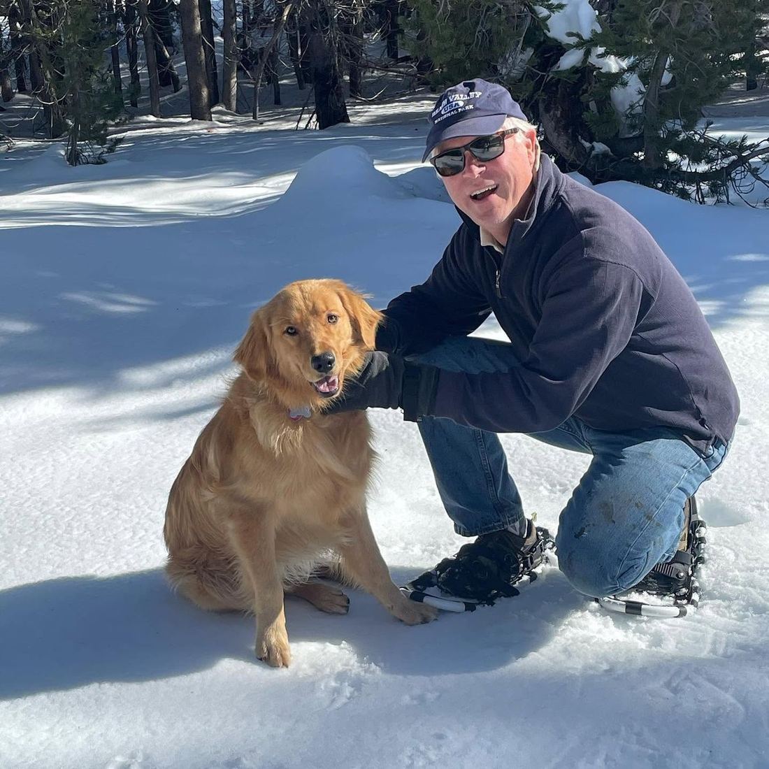 Terry kneeling in the snow beside Buddy, the family's golden retriever