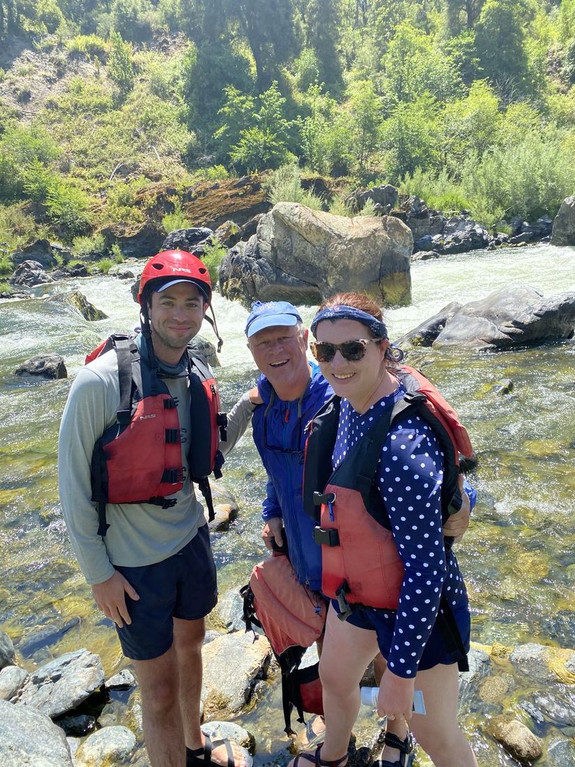 Terry in a life jacket with family on the rocks of a river
